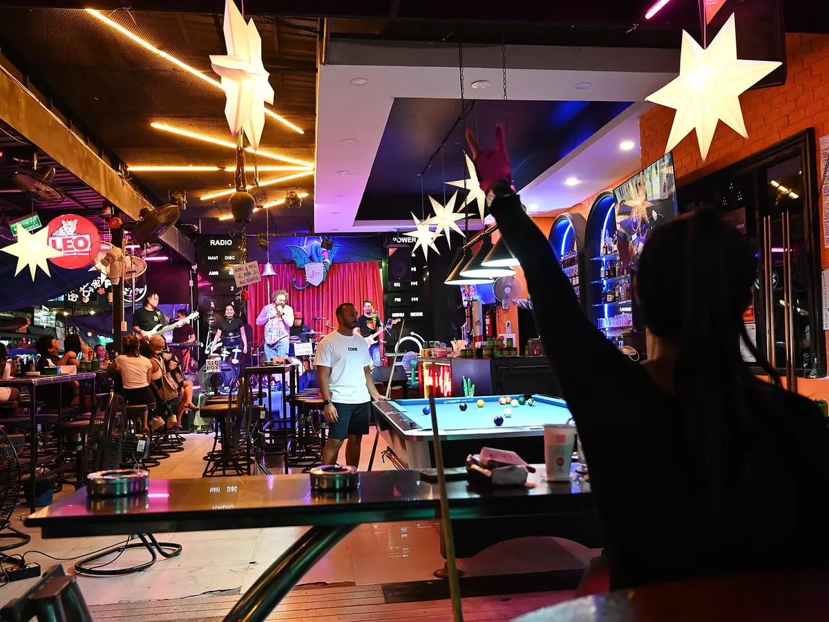 DZ6 0174 A lively bar scene with patrons playing pool and enjoying live music under star-shaped lights.jpg｜PattayaPatrol